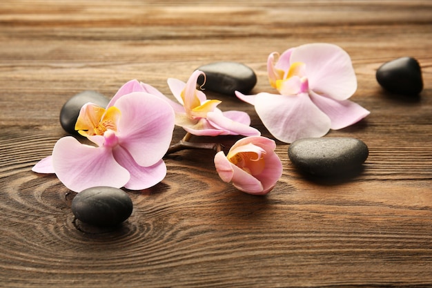 Spa stones and orchid flowers on wooden background