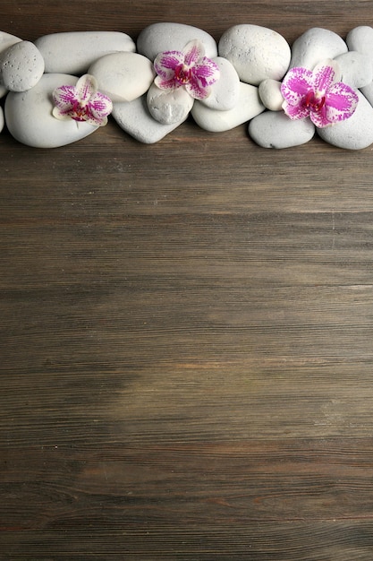 Spa stones and orchid on wooden background