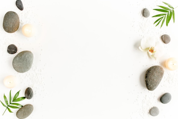 Spa stones palm leaves flower white orchid candle and zen like
grey stones on white background flat