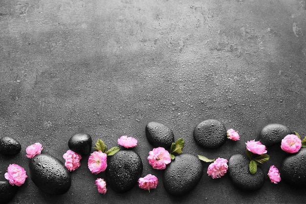 Spa stones and pink flowers on grey background