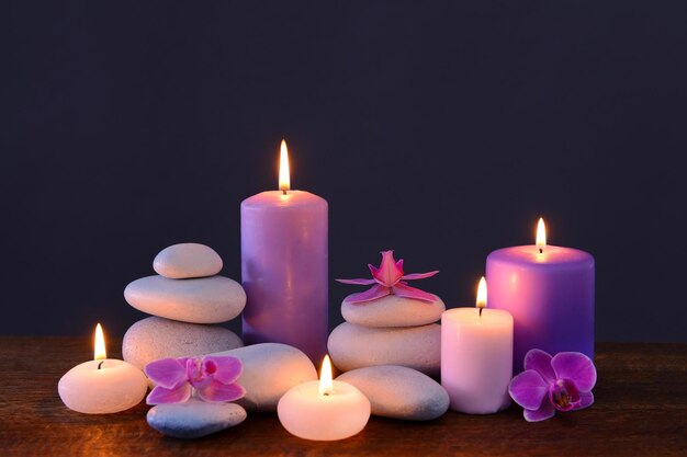 Spa stones with burning candles and flowers on grey background