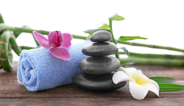 Spa stones with towel tropical flowers and bamboo on white background