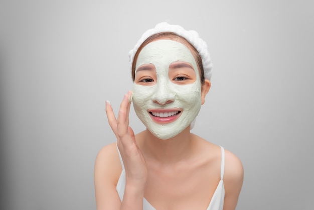 Photo spa teen asian girl applying facial clay mask. beauty treatments. over white background.