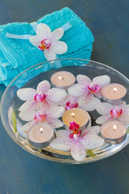 Spa therapie met brandende kaarsen en roze orchideebloemen