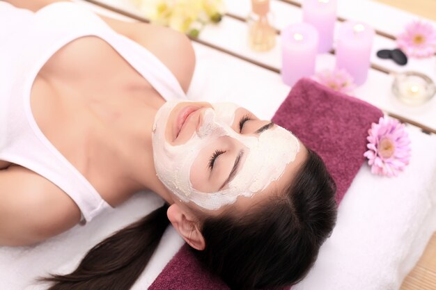 Spa therapy for young woman having facial mask at beauty salon