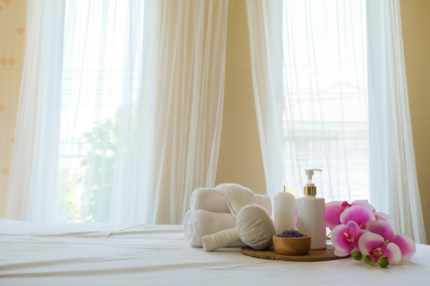 Spa treatment set and aromatic massage oil on bed massage. Thai setting for aroma therapy and massage with flower on the bed