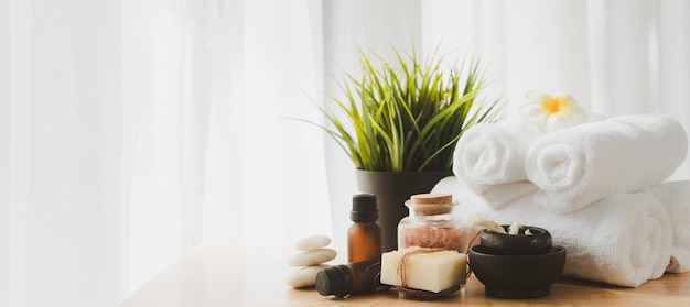 Spa wellness concept, zen stone, candela bianca, sapone al latte, sale rosa, asciugamano, fiori e bottiglia di massaggio con olio sul tavolo in legno sfondo bianco