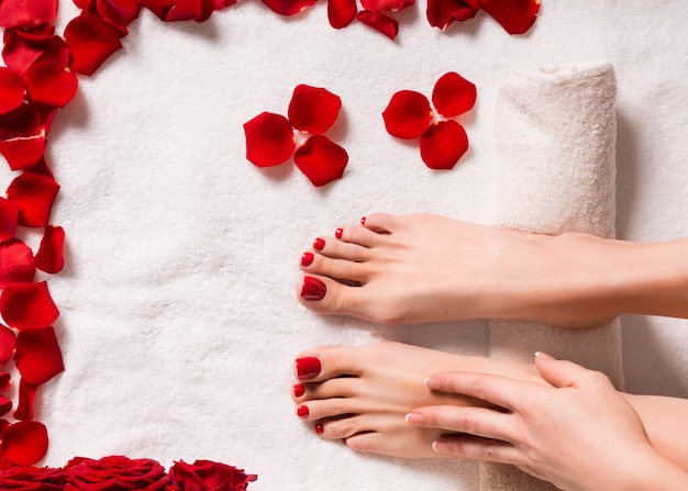 Spa and wellness. Female feet with rose petals on terry towel.