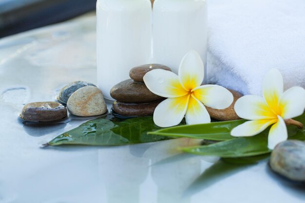 Spa or wellness setting with tropical flowers towel and cream white tubes Body care and spa concept