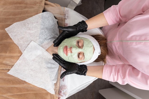 Foto spa donna che applica maschera facciale all'argilla.