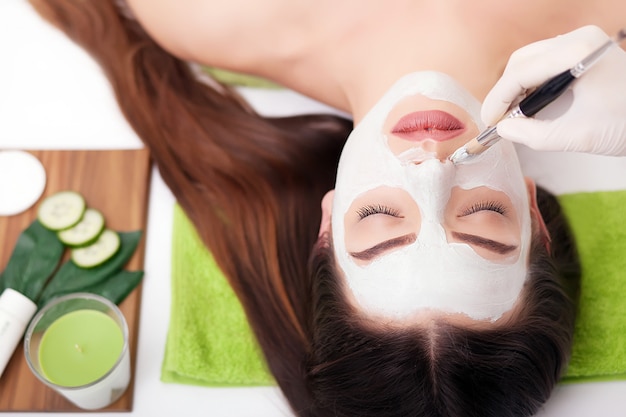 Spa Woman applying Facial cleansing Mask. Beauty Treatments. Clay mask