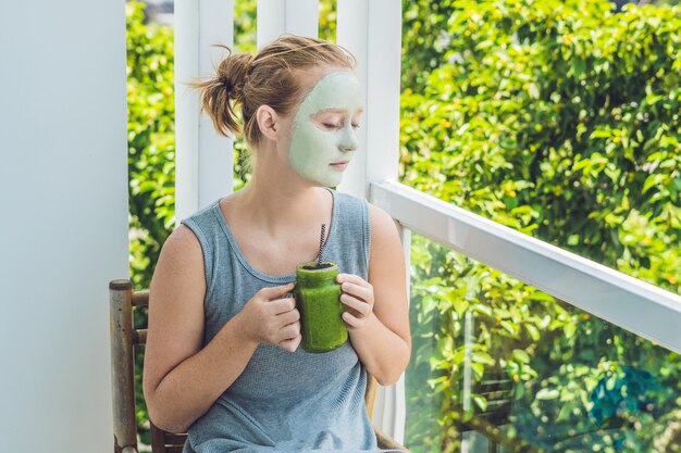 Donna della stazione termale che applica maschera facciale all'argilla verde. trattamenti di bellezza. frullato verde fresco con banana e