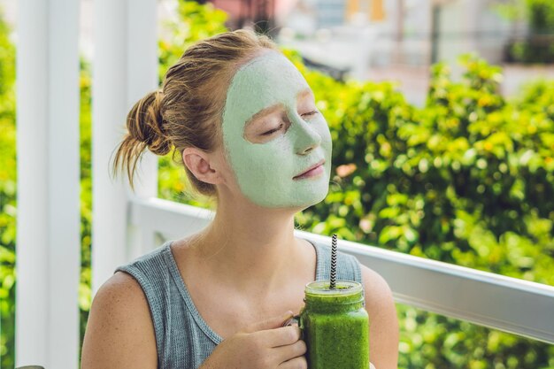 Spa woman applying facial green clay mask beauty treatments fresh green smoothie with banana and