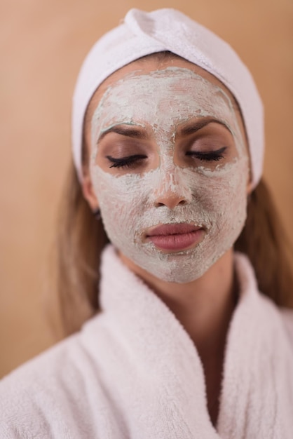 Spa Woman applying Facial Mask  Beauty Treatments  Close up portrait of beautiful girl with a towel on her head applying facial mask