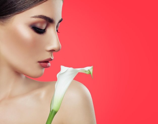 Spa woman with white lily flower on red coral background