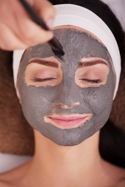spa . young woman with nutrient facial mask in beauty salon, close up