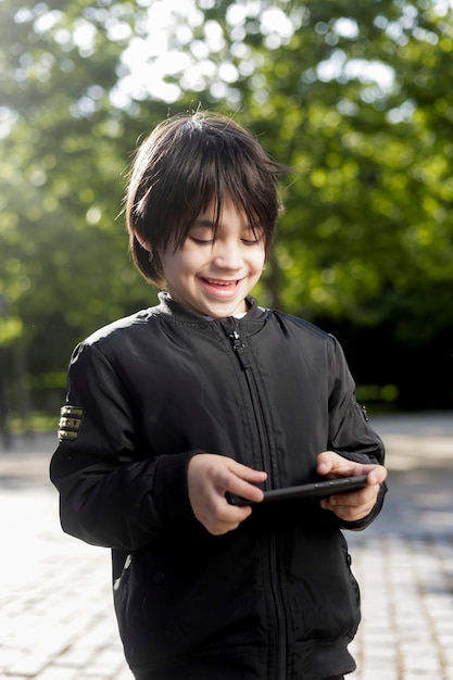 Spaans kind in het park spelen met de mobiele telefoon