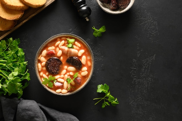 Spaanse asturiana fabada met chorizo en morcilla op zwarte achtergrond