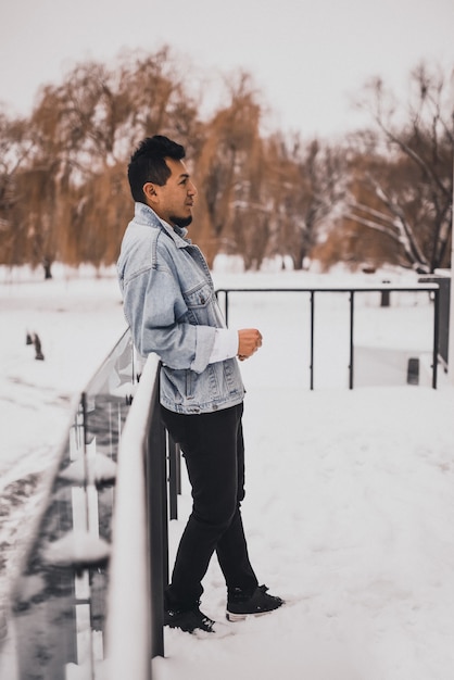 Spaanse brunette man met baard in denim jasje in de winter in het midden van de sneeuw