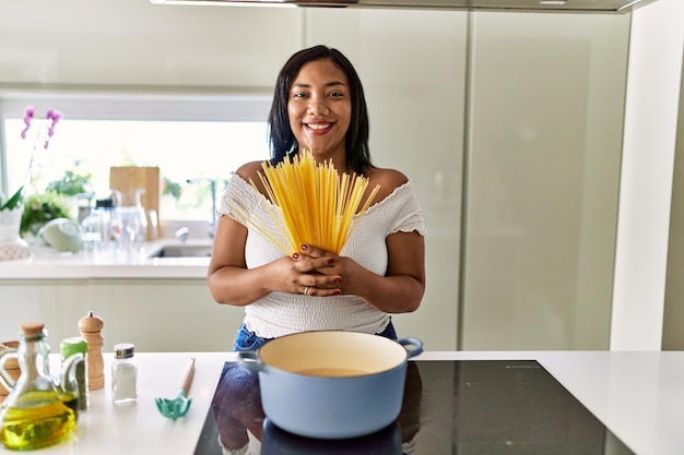 Spaanse donkerbruine vrouw die spaghetti kookt in de keuken