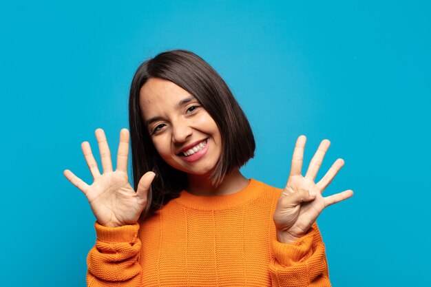 Spaanse en vrouw die vriendelijk glimlacht kijkt, nummer negen of negende met vooruit hand toont, aftellend