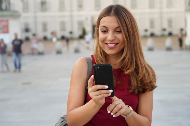 Spaanse jonge vrouw die op straat loopt en online betaalt voor e-commerce op haar mobiele telefoon