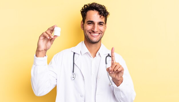 Spaanse knappe man die trots en zelfverzekerd glimlacht en nummer één maakt. arts fles pillen concept
