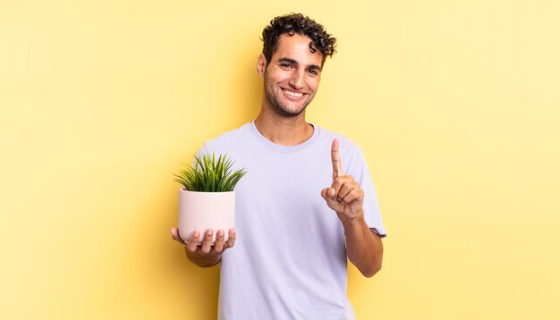 Spaanse knappe man die trots en zelfverzekerd glimlacht en nummer één maakt. decoratief plantenconcept