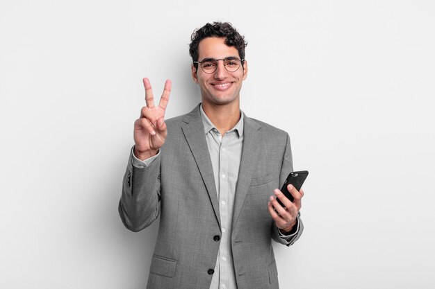 Spaanse knappe man lacht en ziet er gelukkig uit, gebarend overwinning of vrede. zakelijk en telefoonconcept