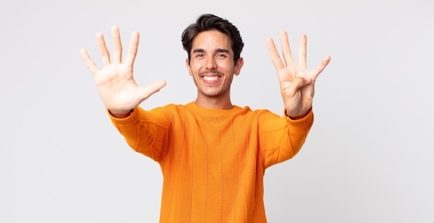 Spaanse knappe man lacht en ziet er vriendelijk uit met nummer negen of negende met de hand naar voren aftellend