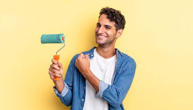 Spaanse knappe man voelt zich gelukkig en staat voor een uitdaging of feest. roller verf concept