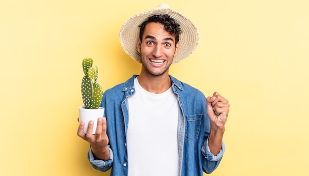 Spaanse knappe man voelt zich geschokt, lacht en viert succes boer en cactusconcept