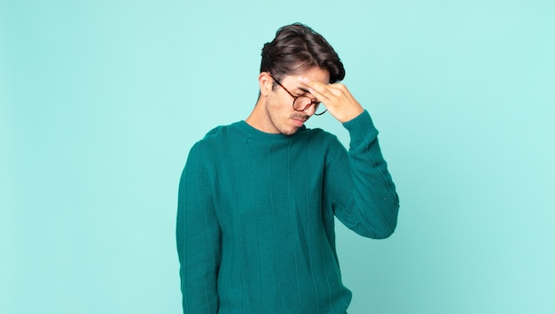 Spaanse knappe man voelt zich gestrest, ongelukkig en gefrustreerd, raakt het voorhoofd aan en lijdt aan migraine of ernstige hoofdpijn
