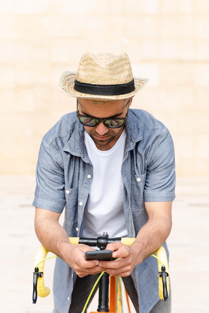 Spaanse man die zijn telefoon controleert op een vintage fiets Social media en digitaal verslavingsconcept