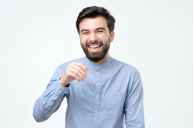 Spaanse man met een blauw shirt die lacht of grijnst met een vrolijke blik