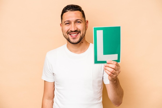 Spaanse man met een bord voor beginnersbestuurders dat op beige achtergrond wordt geïsoleerd