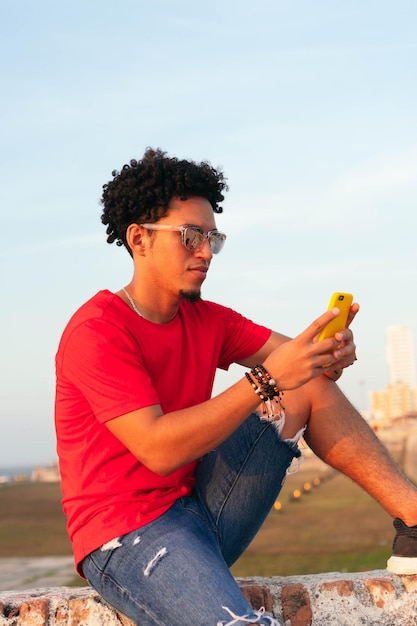 Spaanse man met krullend haar die zijn mobiele telefoon buiten controleert