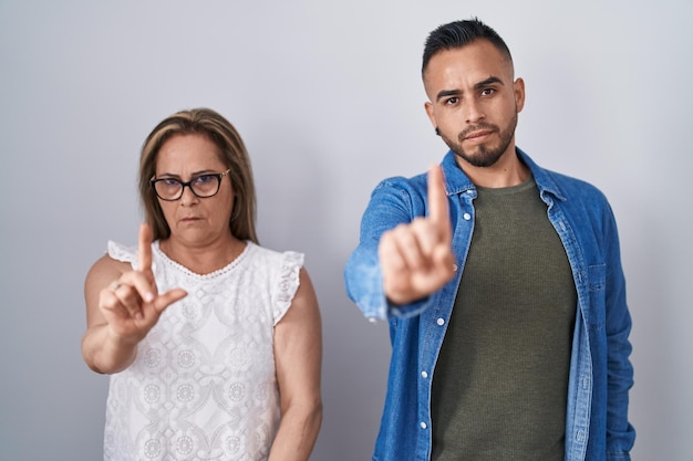 Spaanse moeder en zoon staan samen met vinger omhoog en boze uitdrukking, geen gebaar tonend