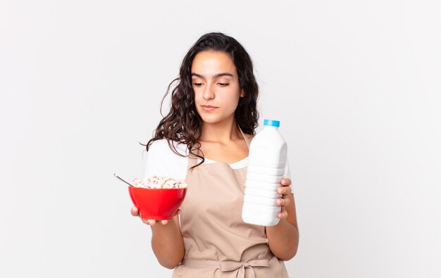 Spaanse mooie chef-kokvrouw die een ontbijtkom met melk houdt