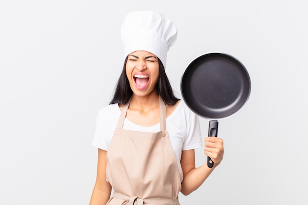 Spaanse mooie chef-kokvrouw die een pan houdt