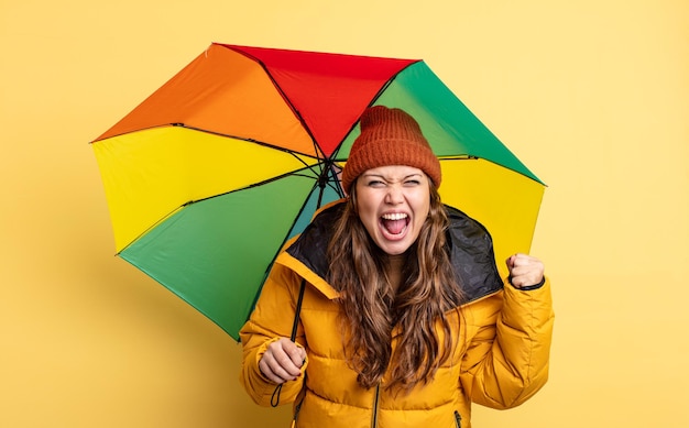 Spaanse mooie vrouw die agressief met een boze uitdrukking schreeuwt. paraplu concept