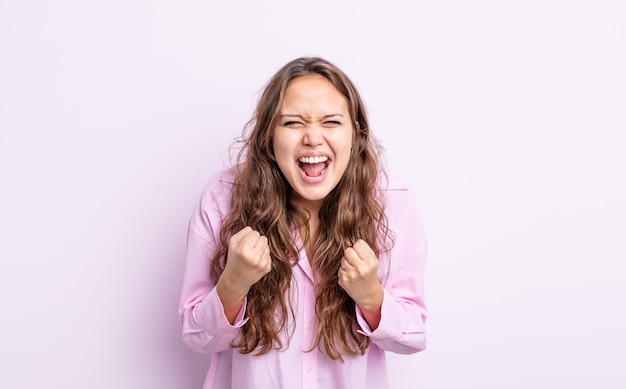 Spaanse mooie vrouw die agressief schreeuwt met een geïrriteerde, gefrustreerde, boze blik en strakke vuisten, woedend voelend