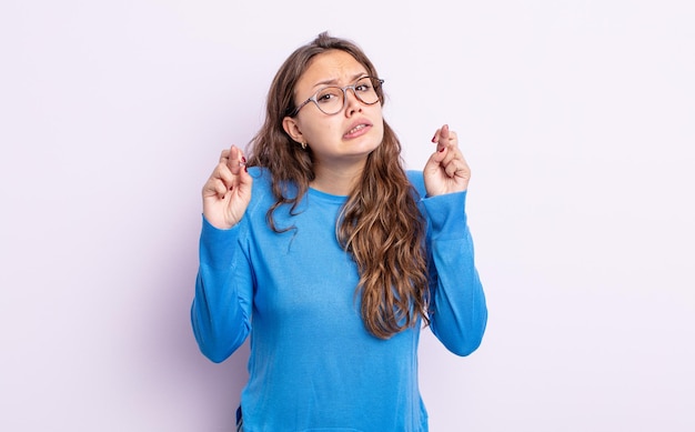 Spaanse mooie vrouw die angstig vingers kruist en hoopt op veel geluk met een bezorgde blik