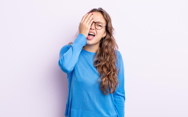 Spaanse mooie vrouw die er slaperig, verveeld en geeuwend uitziet, met hoofdpijn en één hand die het halve gezicht bedekt