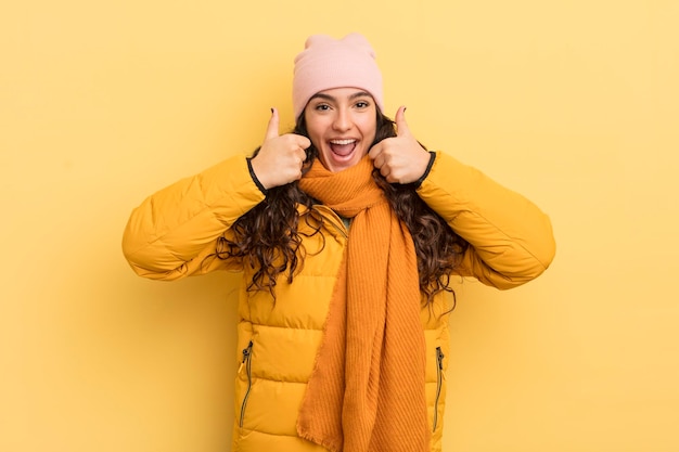 Spaanse mooie vrouw die in het algemeen lacht en er gelukkig positief zelfverzekerd en succesvol uitziet met beide duimen omhoog