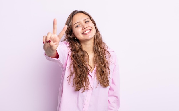 Spaanse mooie vrouw die lacht en er vriendelijk uitziet, nummer twee of seconde toont met de hand naar voren, aftellend