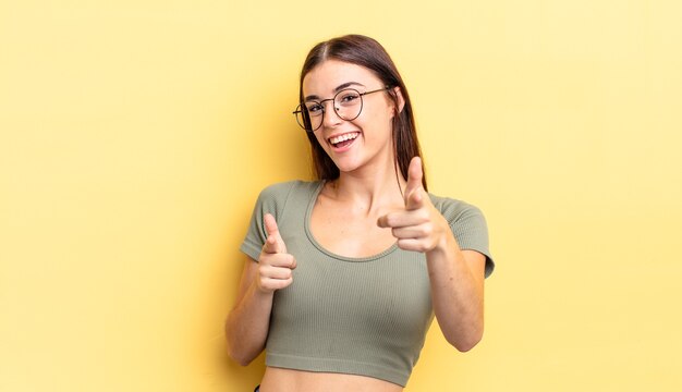 Spaanse mooie vrouw die lacht met een positieve, succesvolle, gelukkige houding die naar de camera wijst en een pistoolteken maakt met handen