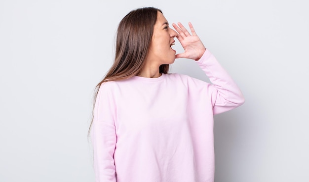 Spaanse mooie vrouw die luid en boos schreeuwt om de ruimte aan de zijkant te kopiëren, met de hand naast de mond