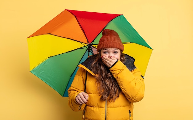 Spaanse mooie vrouw die mond bedekt met handen met een geschokt. paraplu concept