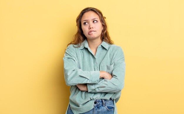 Spaanse mooie vrouw die twijfelt of denkt, lip bijt en zich onzeker en nerveus voelt, op zoek naar ruimte aan de zijkant